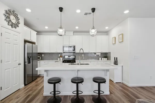 a kitchen with stainless steel appliances kitchen island a table chairs sink and wooden floor