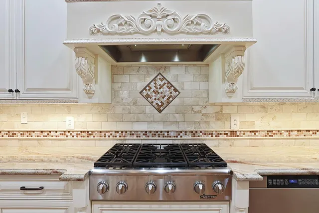 a kitchen with granite countertop a stove and white cabinets