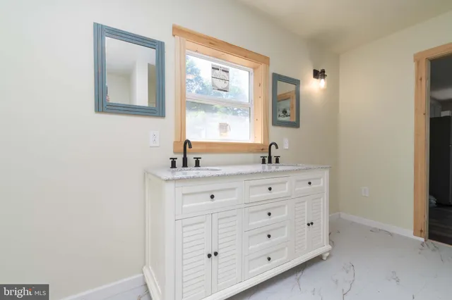 a bathroom with a granite countertop double vanity sink a mirror and