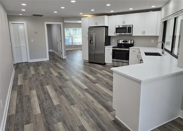a view of an empty room with wooden floor and a ceiling fan
