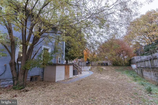 a view of a house with a large tree and wooden fence