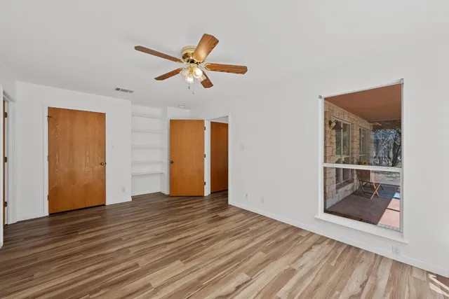 a view of empty room with wooden floor and ceiling fan