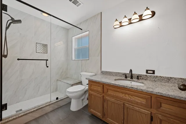a bathroom with a granite countertop sink toilet and shower