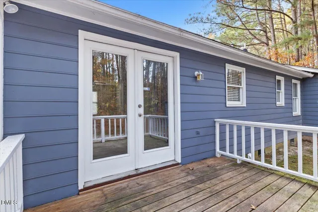 a view of backyard with wooden deck and a patio