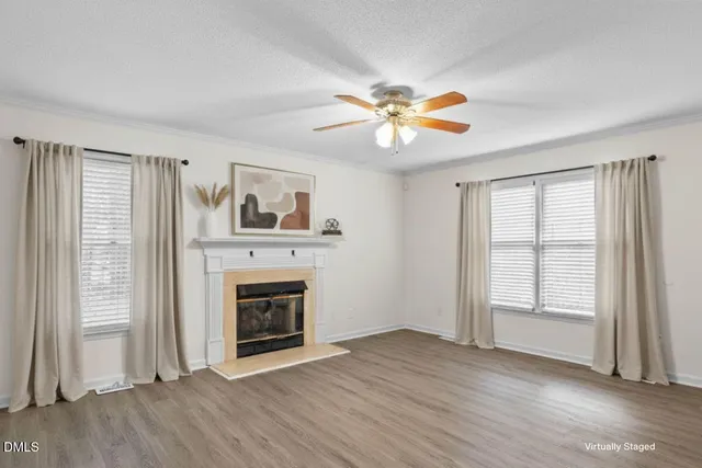 an empty room with windows fireplace and fan