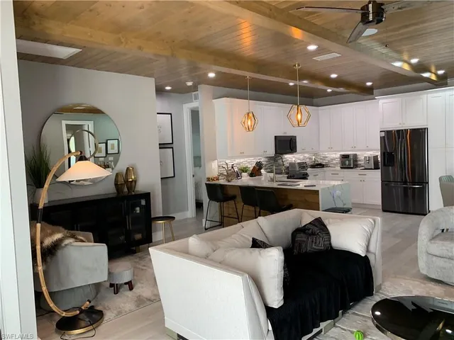 a kitchen with a refrigerator a sink dishwasher a dining table and chairs with wooden floor