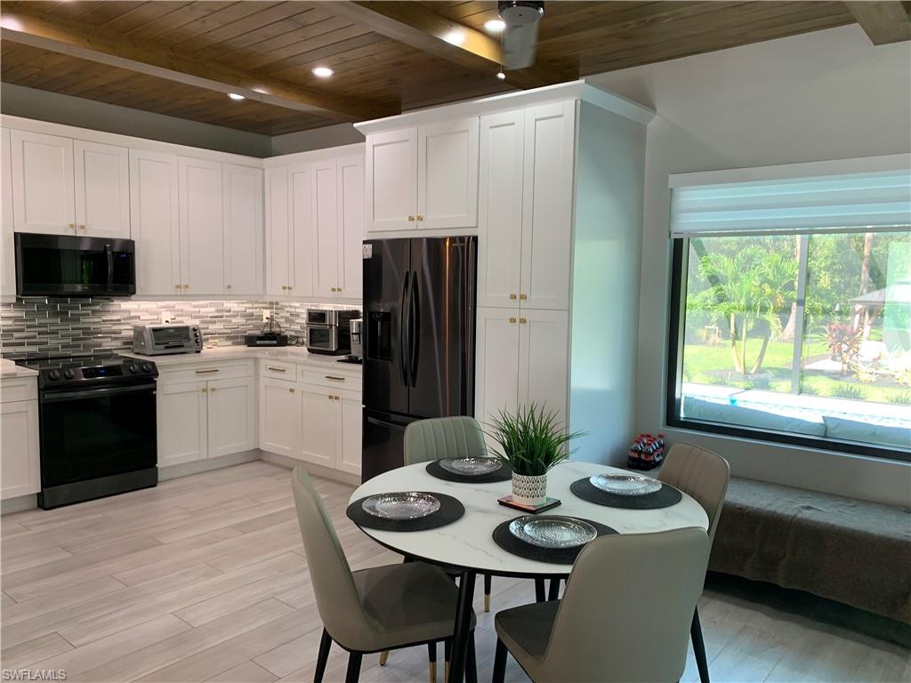 3651 29th Avenue Southwest Naples, FL 34117 - Photo 23 of 49 a kitchen with a table chairs stove and refrigerator