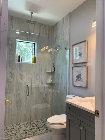 a bathroom with a granite countertop sink a toilet and shower