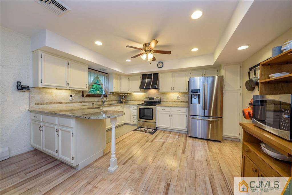 4 Tower Road Pompton Lakes, NJ 07442 - Photo 9 of 25 a kitchen with stainless steel appliances a refrigerator a stove a sink dishwasher and a dining table with wooden floor
