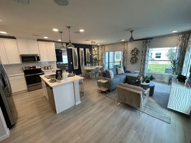 a living room with furniture kitchen and a wooden floor