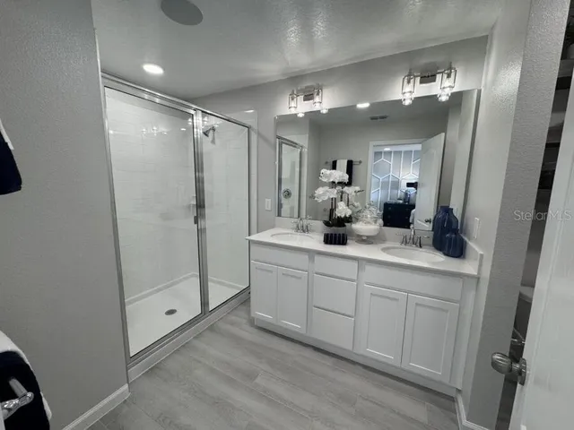a bathroom with a double vanity sink mirror and shower