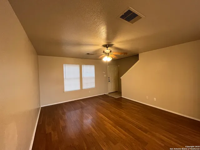 a view of an empty room with wooden floor and a window
