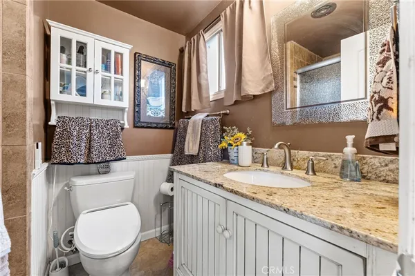 a bathroom with a granite countertop toilet sink and mirror