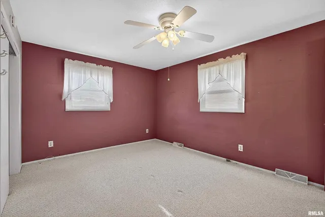 an empty room with windows and a chandelier fan