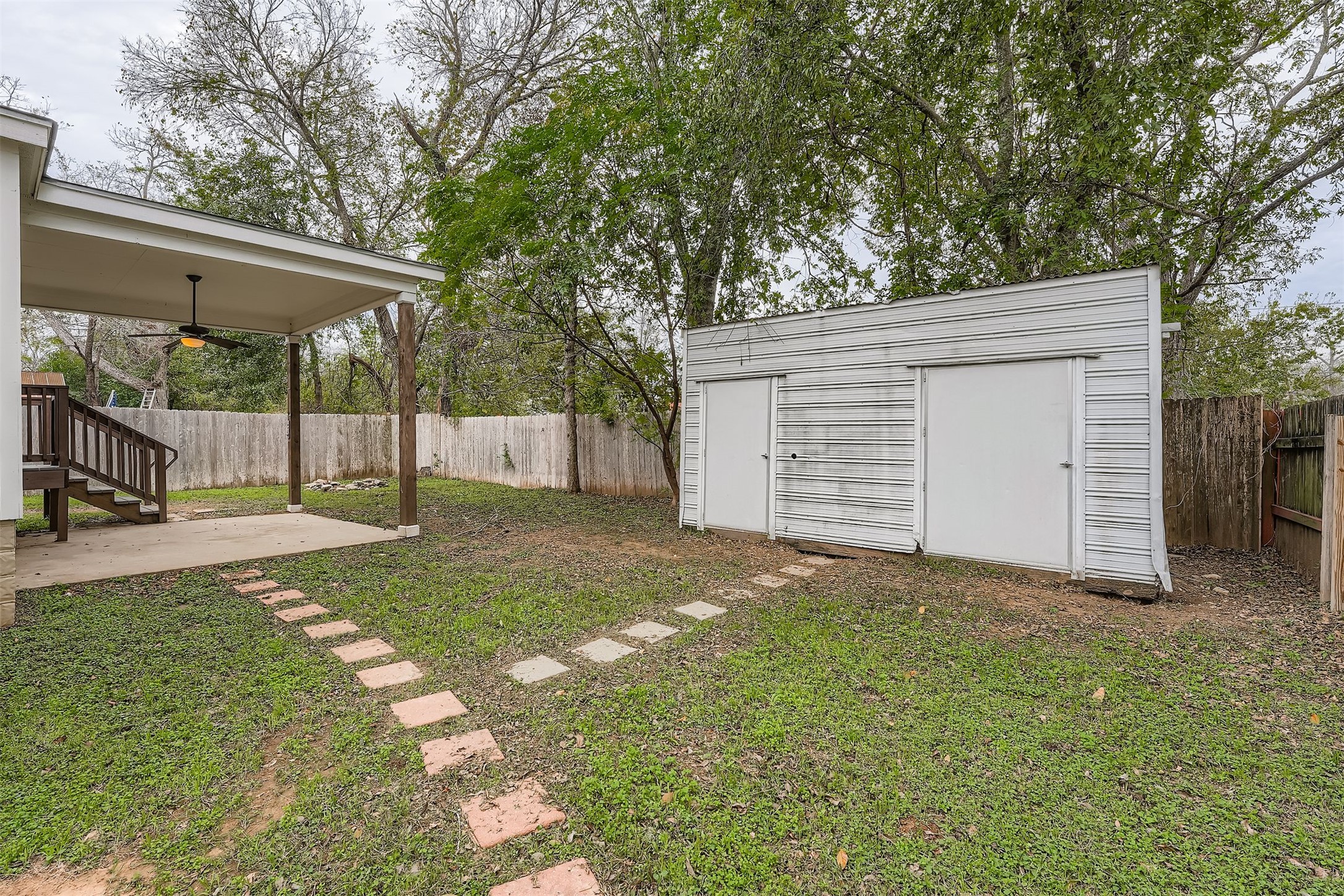 304 South Main Street Elgin, TX 78621 - Photo 25 of 25 Fenced backyard featuring ceiling fan and a storage unit