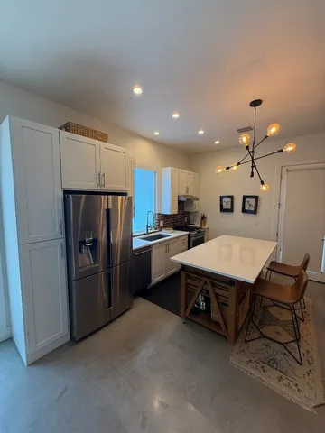 a kitchen with refrigerator and chairs