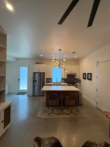 a view of kitchen center island stainless steel appliances wooden floor and living room view
