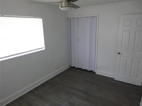 an empty room with wooden floor cabinet and windows