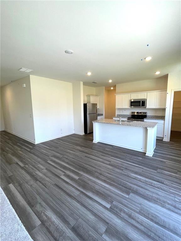 24 Rowlett Place Winder, GA 30680 - Photo 3 of 17 a view of kitchen and empty room with wooden floor