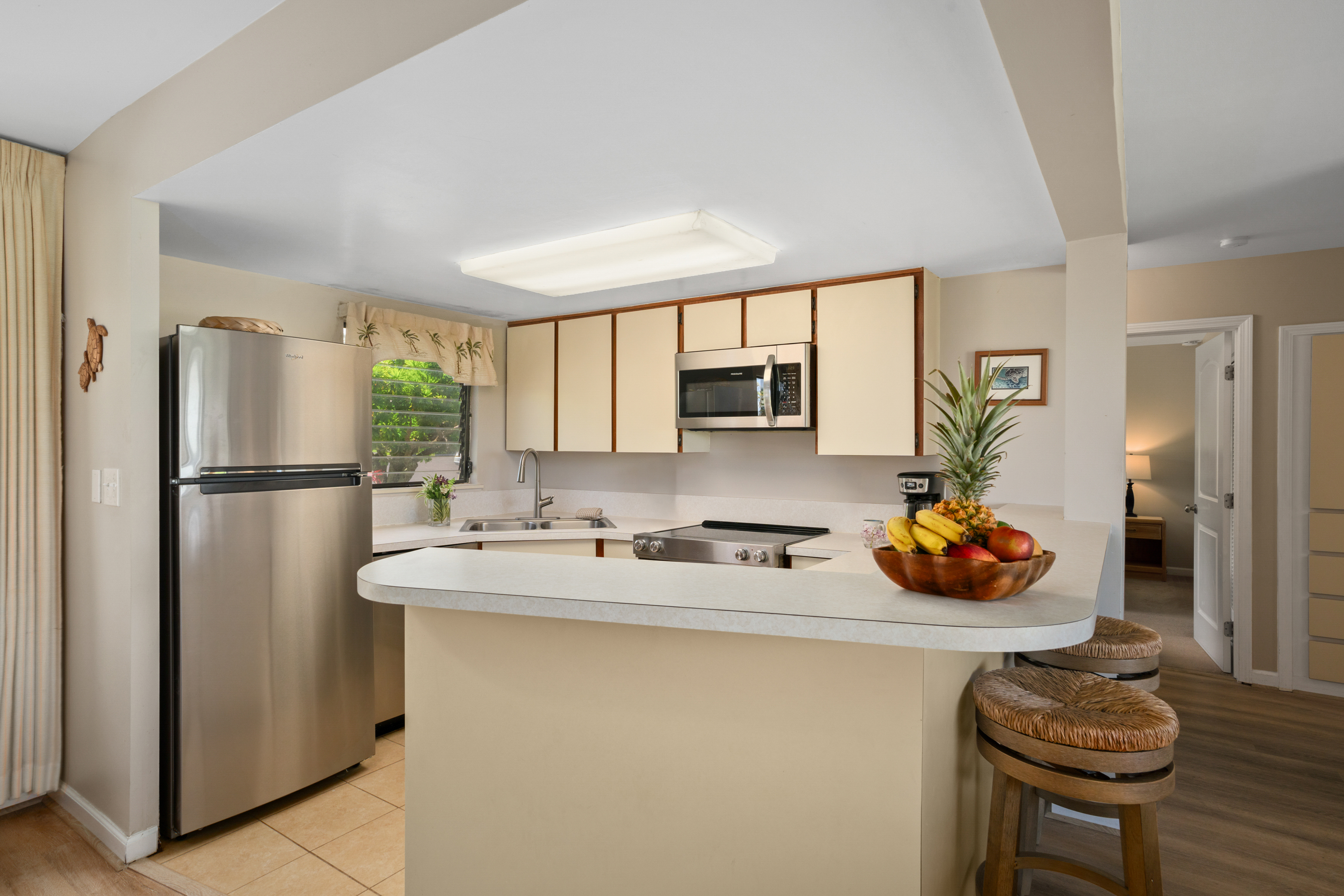 3830 Edward Road, Unit 12D Princeville, HI 96722 - Photo 9 of 30 a kitchen with stainless steel appliances granite countertop a sink a refrigerator and a refrigerator