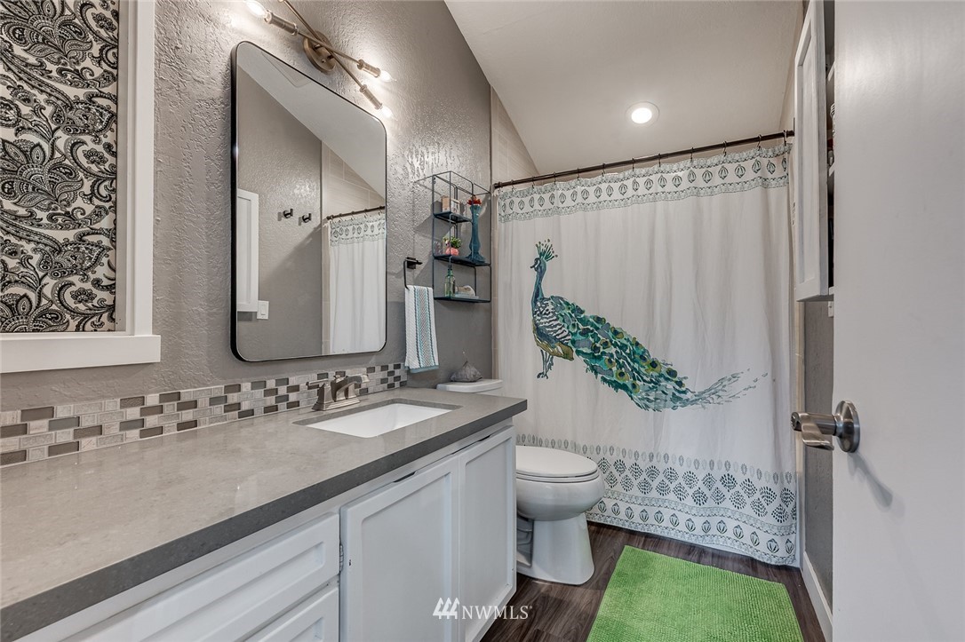 6918 Lower Ridge Road, Unit B Everett, WA 98203 - Photo 21 of 25 a bathroom with a granite countertop sink a large mirror and shower