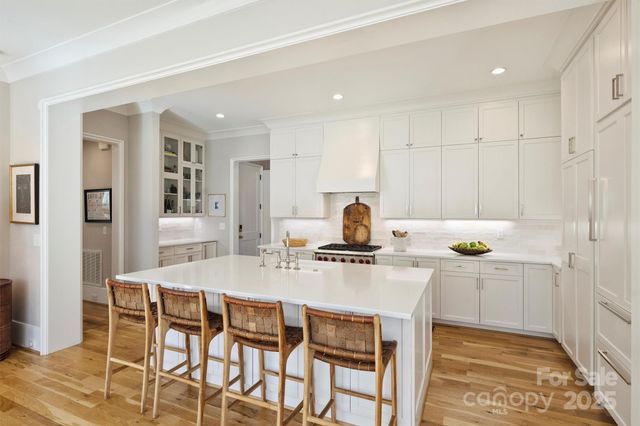 a kitchen with stainless steel appliances kitchen island a table chairs sink and cabinets