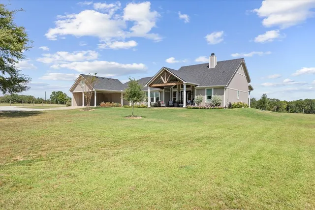 a view of a house with a big yard and large trees
