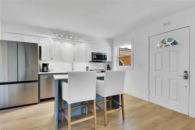 a kitchen with stainless steel appliances granite countertop a refrigerator a stove a microwave oven a sink with island and chairs