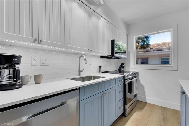 a kitchen with a sink dishwasher and cabinets with wooden floor