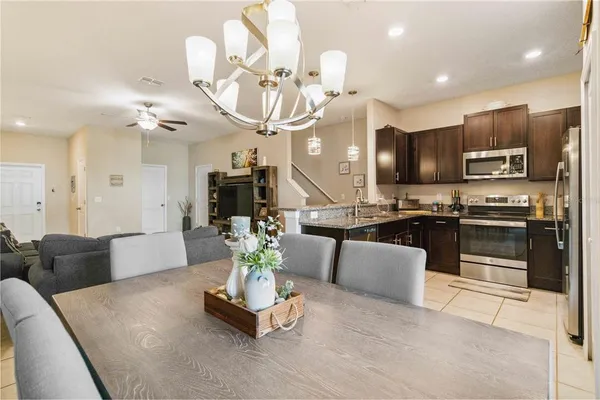 a kitchen with stainless steel appliances kitchen island granite countertop a refrigerator a stove a sink and a dining table with wooden floor