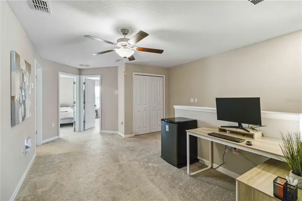 a view of a workspace with furniture and a ceiling fan