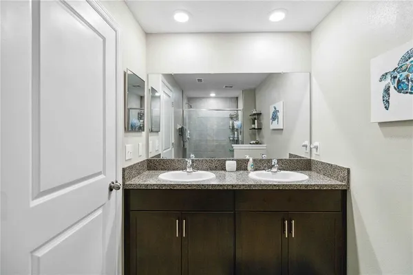 a bathroom with a granite countertop double vanity sink and a mirror
