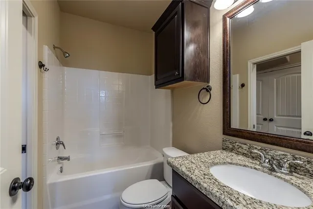 a bathroom with a granite countertop sink toilet and shower