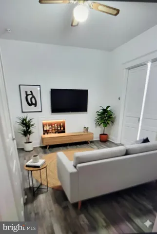 a view of an empty room with wooden floor and a ceiling fan