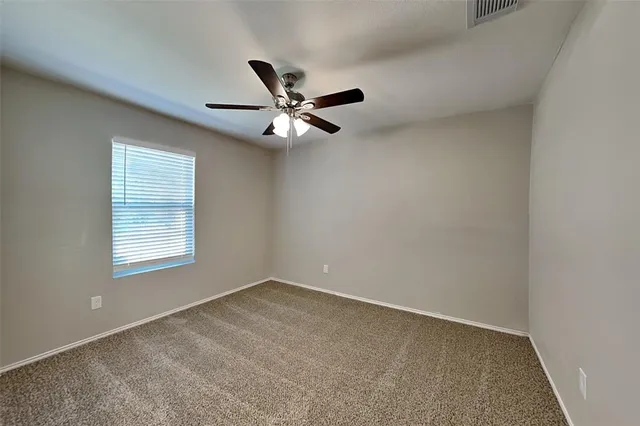 an empty room with a window and a fan