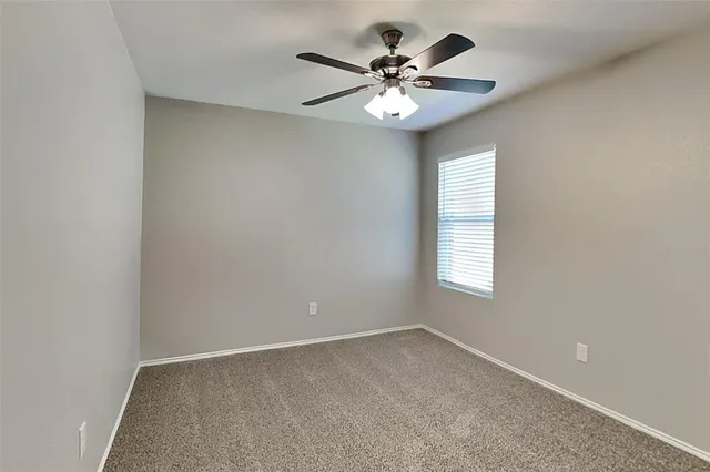 an empty room with a chandelier fan and windows
