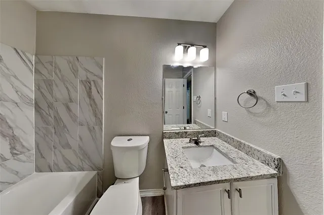 a bathroom with a granite countertop sink a toilet and mirror