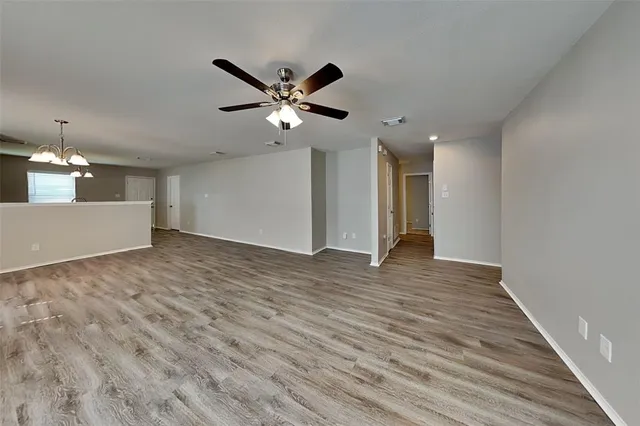 a view of an empty room with wooden floor and a ceiling fan