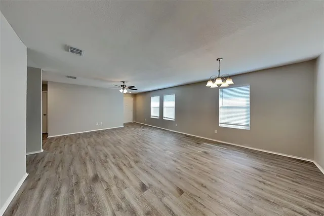 an empty room with wooden floor and chandelier