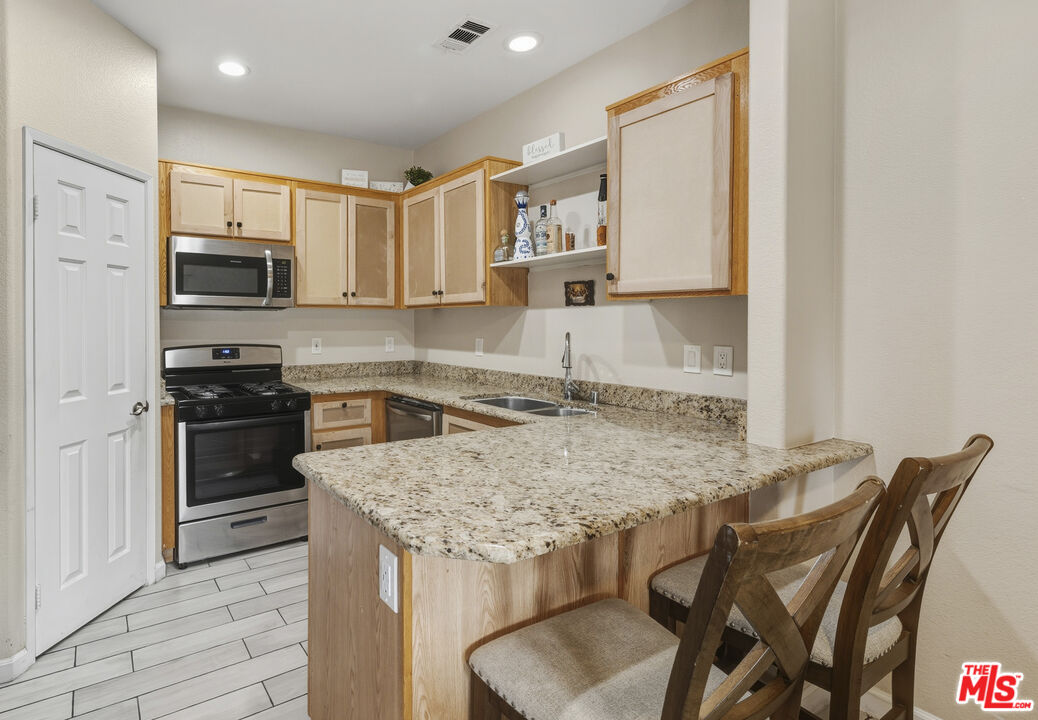 47395 Monroe Street, Unit 254 Indio, CA 92201 - Photo 10 of 21 a kitchen with stainless steel appliances granite countertop a stove top oven a sink a dining table and chairs