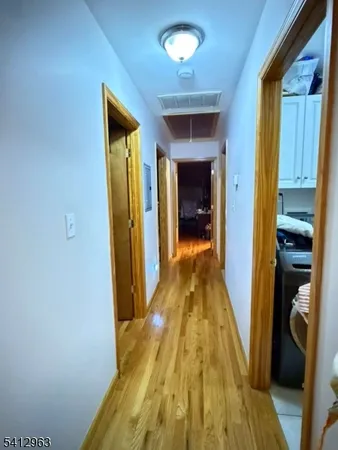 a view of a hallway with wooden floor and a chandelier