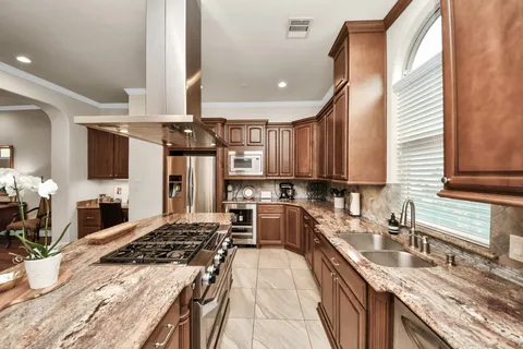 a kitchen with stainless steel appliances granite countertop a sink stove and cabinets