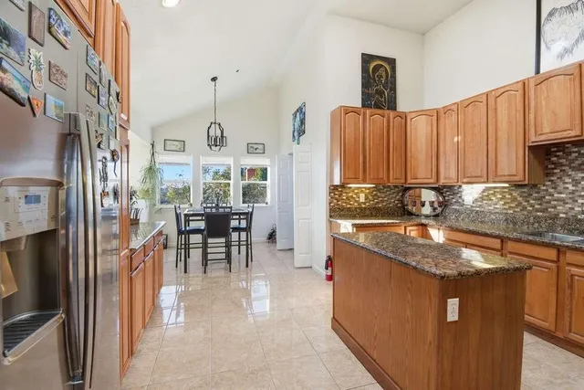 a kitchen with stainless steel appliances granite countertop a stove top oven a sink dishwasher a dining table and chairs with wooden floor