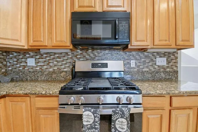 a kitchen with granite countertop cabinets stove top oven and microwave