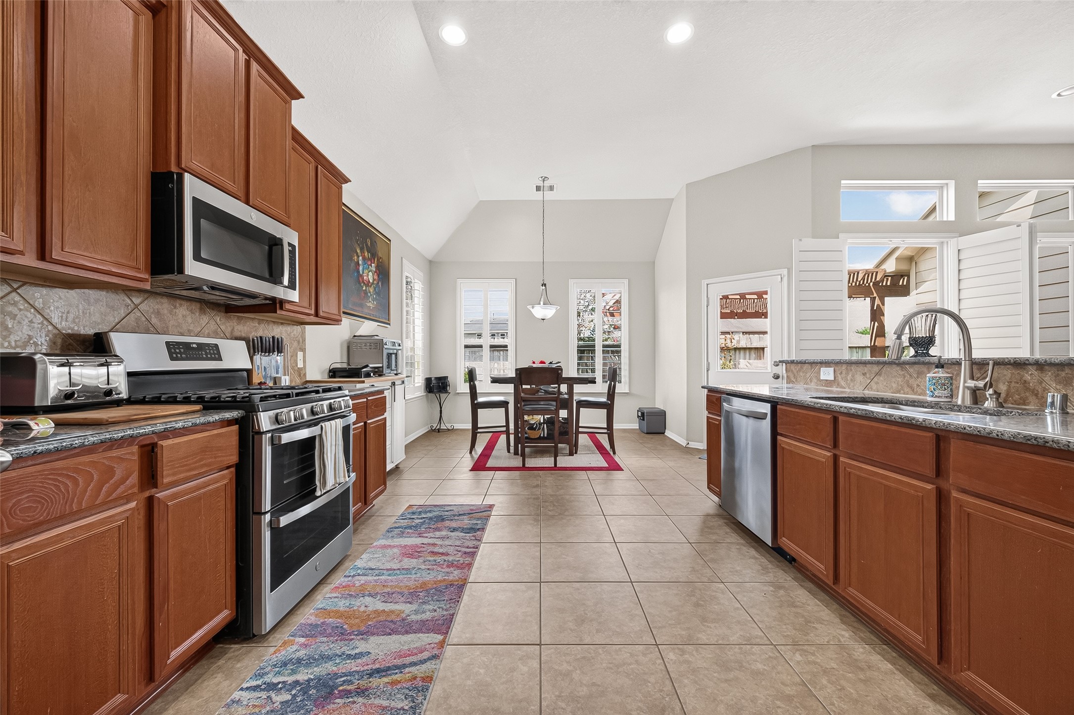4910 Culver Lane Rosenberg, TX 77471 - Photo 25 of 50 See this spacious, well-lit kitchen with modern stainless steel appliances, 42" wooden cabinetry, and a tile floor. It features a great breakfast area with large windows, providing plenty of natural light, and a view of the landscaped backyard.