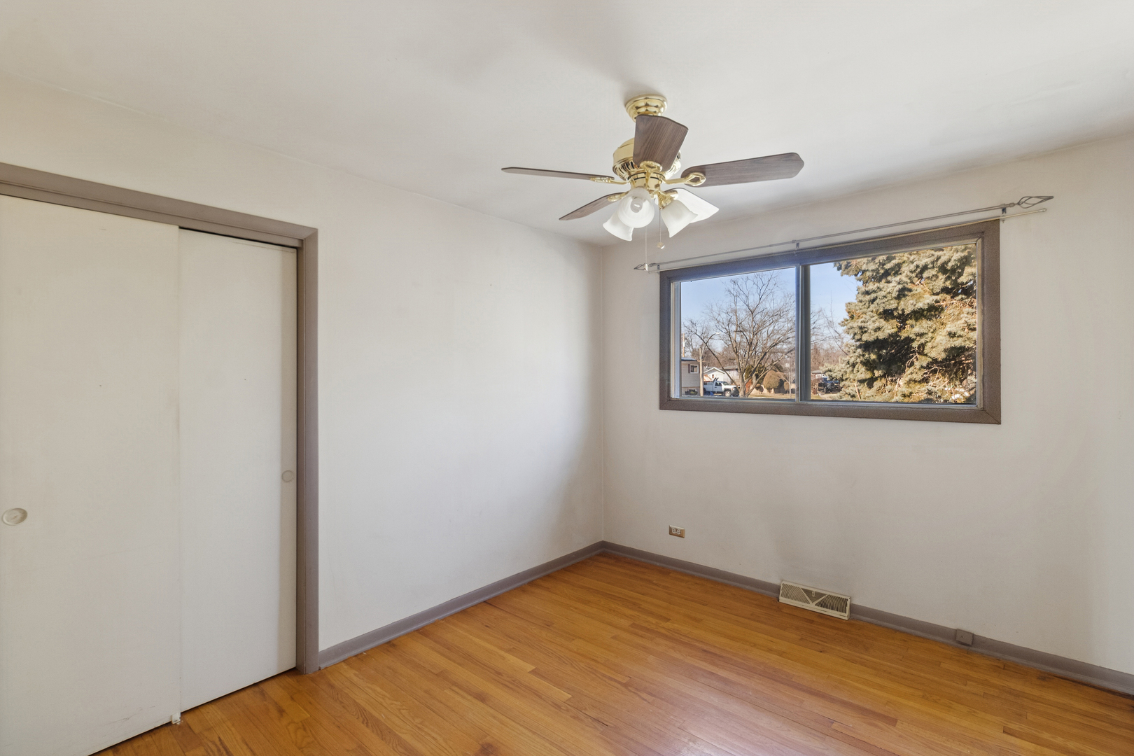 431 Ardmore Terrace Addison, IL 60101 - Photo 9 of 15 an empty room with wooden floor chandelier fan and windows
