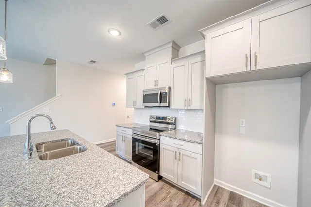 a kitchen with stainless steel appliances granite countertop a stove a microwave and a white cabinets