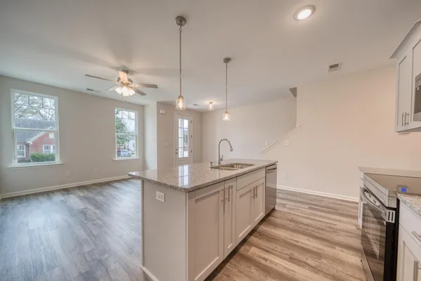 a kitchen with stainless steel appliances granite countertop a sink a window and a chandelier
