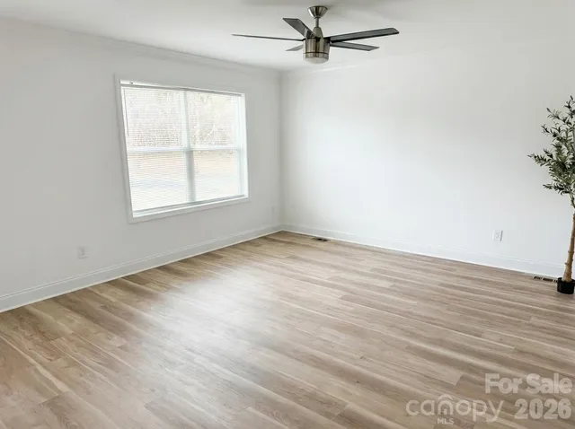 an empty room with wooden floor fan and windows