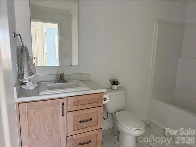 a bathroom with a granite countertop toilet sink and mirror